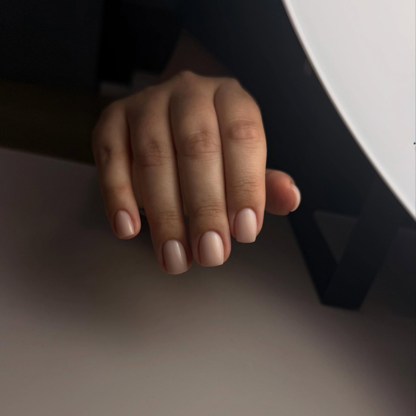 Hand met korte, naturel BIAB-nagels in een warme nude tint