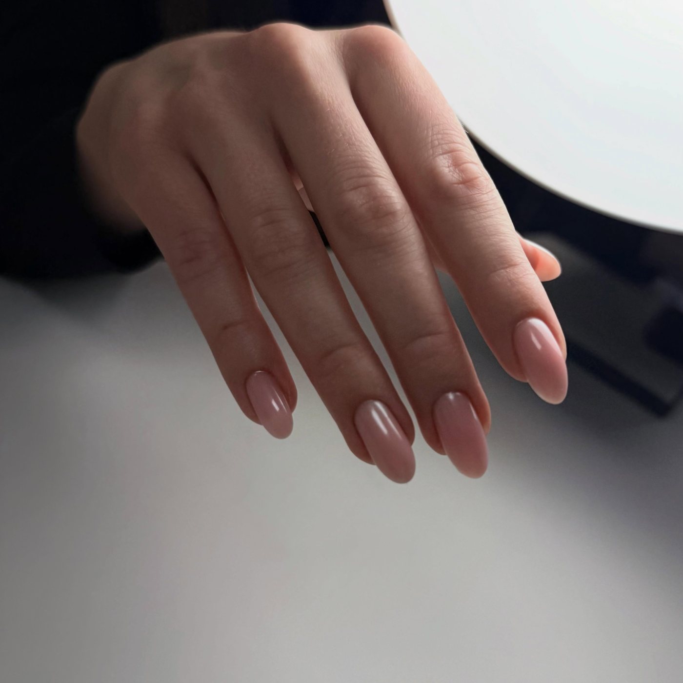 Hand met langere, rosé nude nagels in amandelvorm